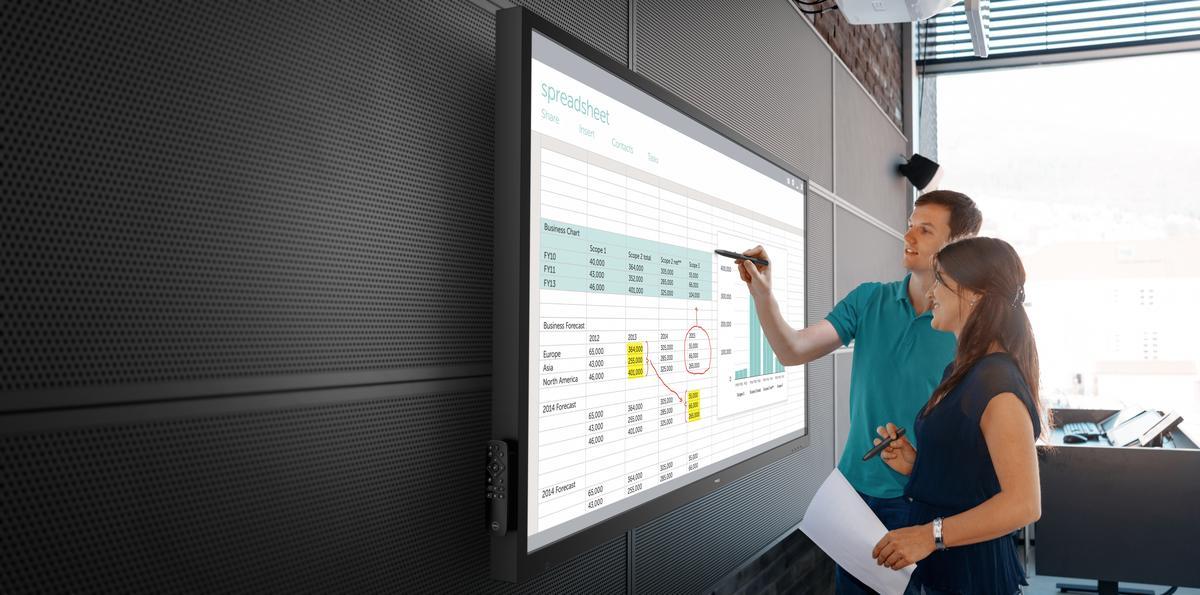 A woman and a man are looking at data on a on a Dell 70 (Model C7017T) 70-inch conference room monitor.