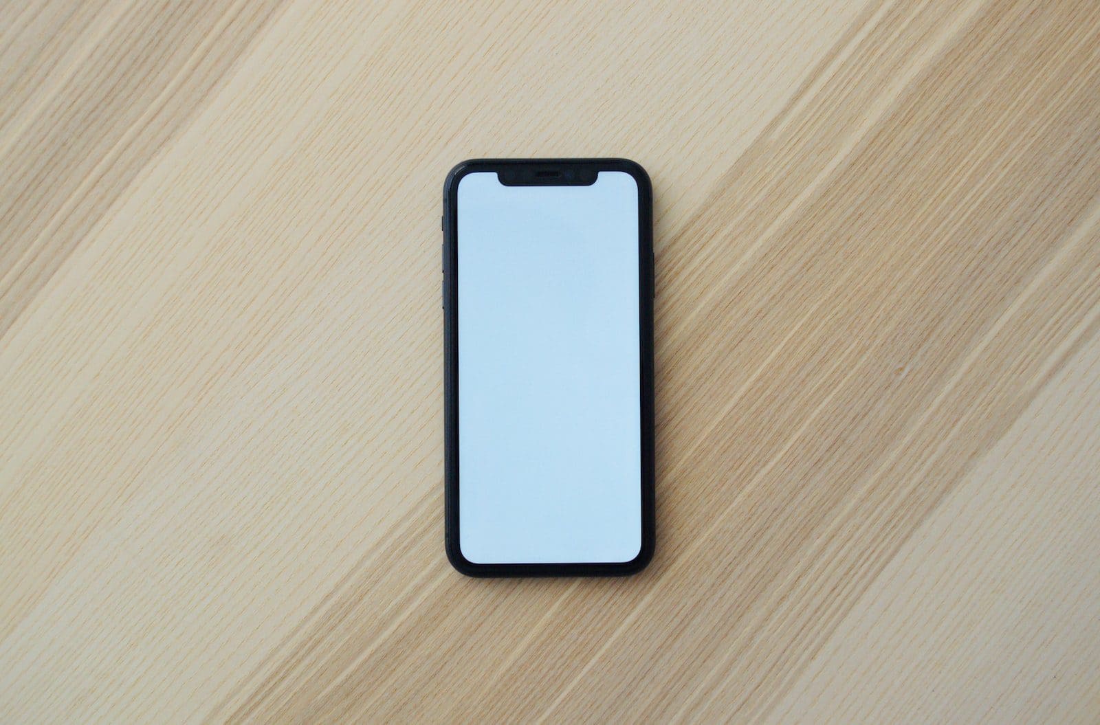 smartphone putih di atas meja kayu cokelat